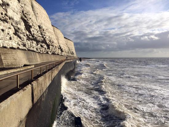 This image shows the sea crashing against the wall. To the left, is the path I walk along every day, and above that are the chalk cliffs. The sky is a mixture of cloud and blue.