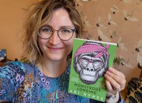 Author Abi Hynes holding up her short story collection Monstrous Longing
